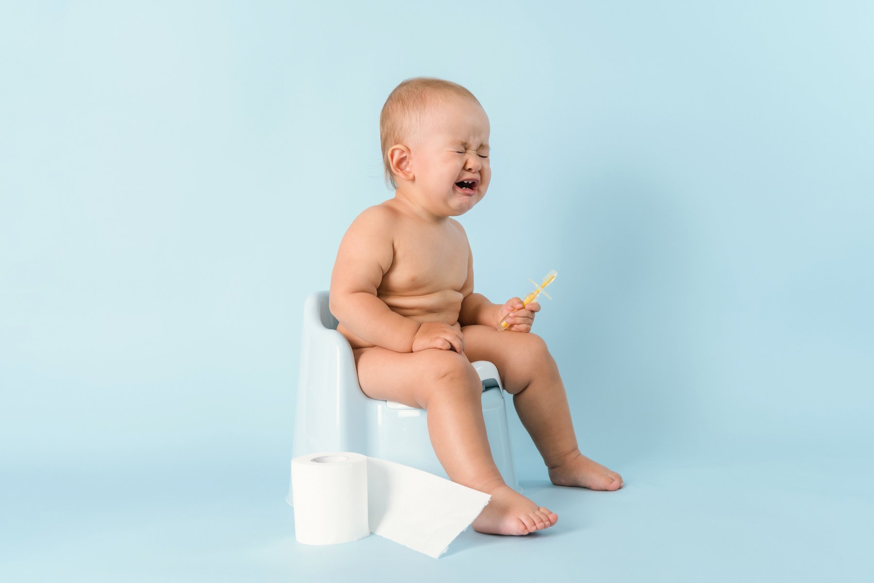 A small child is sitting on a potty and crying. Diarrhea and bloating in a newborn.